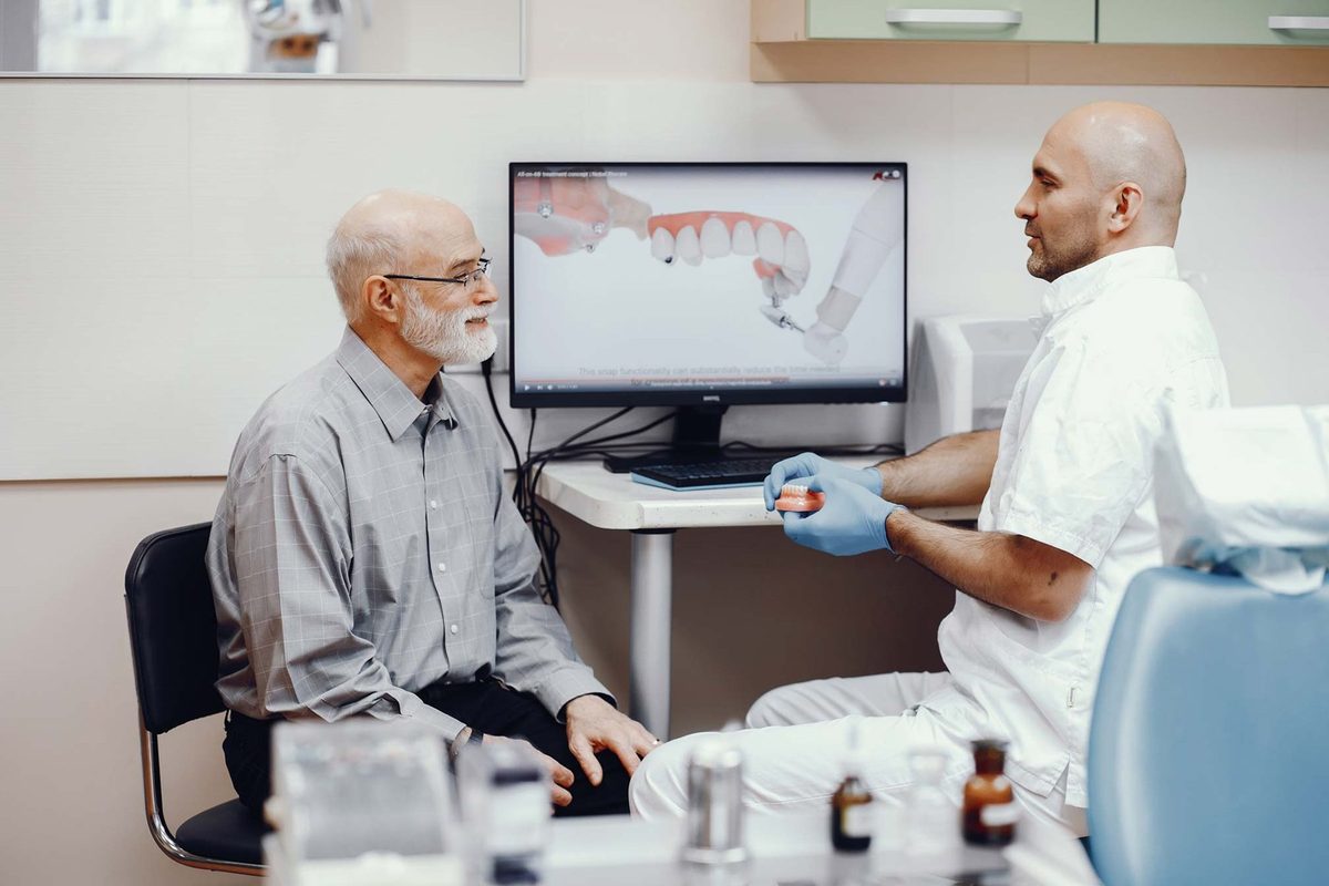 A dentist talking a patient through a scan of their teeth on a monitor during a consultation